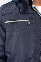 Campera de nylon color azul marino con cierre frontal completo, capucha desmontable y puños elásticos. Presenta bolsillos con cierre y logo aplicado en la manga.