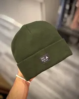 Gorro de lana verde con etiqueta de marca cosida en el frente.