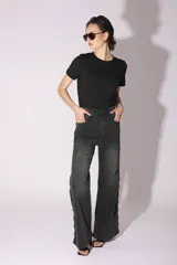 Pantalón de jean gris oscuro de corte acampanado, con tachas metálicas plateadas en los laterales.