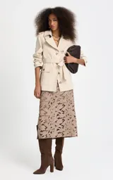 Trench corto Le Lis Blanc modelo Georgia, color beige, de corte recto, con cuello con solapa, doble botonadura frontal con botones carey, bolsillos delanteros con solapa y cinturón ajustable para la cintura.
