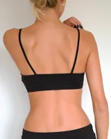 Bra estilo bandeau con breteles finos ajustables, confeccionado en tela lisa con delicados detalles de encaje en los bordes superior e inferior.