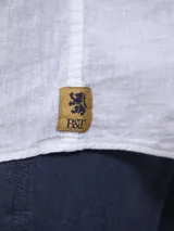 Camisa de lino blanca de manga larga con cuello mao, cierre frontal con botones y un bolsillo aplicado en el pecho.