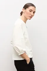 Remera blanca con mangas abullonadas y puños elásticos, de corte recto y escote redondo.