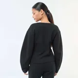 Buzo de cuello redondo negro, con mangas largas abullonadas y costuras frontales marcadas.