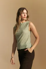 Top sin mangas de jacquard color negro, con cuello cerrado y silueta recta. Presenta una textura trabajada con relieve y una terminación suavemente ondulada en el ruedo.