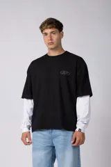 Remera de manga larga con diseño de doble capa, que simula una remera negra de manga corta sobre una blanca de manga larga. Presenta un pequeño logo gráfico en el pecho y una etiqueta pequeña en el puño.