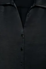 Camisa corta de tejido satinado color marrón, con cuello solapa, escote en pico y manga larga. Presenta cierre frontal con botones forrados a tono.