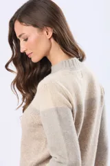 Buzo tejido de punto con diseño de bloques de color en tonos rosa, beige y gris. Presenta cuello redondo, mangas largas y corte holgado.