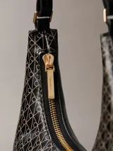 Cartera de hombro de Calvin Klein en color negro con estampado integral geométrico y de monograma. Cuenta con cierre de cremallera superior y una correa ajustable.