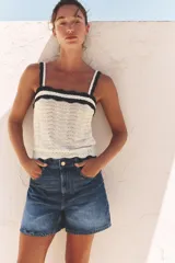 Shorts de tiro alto estilo mom fit, confeccionados en denim blanco, con diseño de cinco bolsillos, cierre frontal con cremallera y botón metálico.