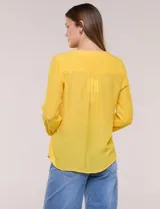 Blusa de calce relajado color salmón, confeccionada en tela liviana con textura sutil. Presenta escote en V con abotonadura frontal, bolsillo parche en el pecho, mangas largas regulables con presilla y ruedo con opción de anudar en el frente.