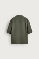 Camisa tipo kimono de corte relaxed fit, color celeste, confeccionada en tejido fluido de viscosa y lino. Presenta cuello con solapas de muesca, manga corta y cierre frontal cruzado con doble botonadura.