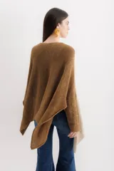 Poncho de tejido de punto con diseño oversize y aberturas laterales. Presenta un acabado con destellos brillantes y cuello redondo amplio.