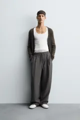 Pantalón de corte relajado, color gris oscuro, con cintura elástica ajustable mediante cordón y pliegues frontales. Presenta bolsillos laterales y bolsillos traseros de parche con pespuntes contrastantes.