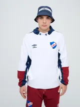 Canguro deportivo Umbro del Club Nacional de Football, modelo Evoque. Diseño con bloques de color blanco en el torso, azul en la capucha, laterales y parte superior de las mangas, y rojo en los puños. Incluye capucha con cordón ajustable, logo de Umbro y escudo del club bordados en el pecho.