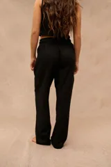 Pantalón largo negro de corte holgado, con cintura elástica ajustable mediante cordón y bolsillos laterales.