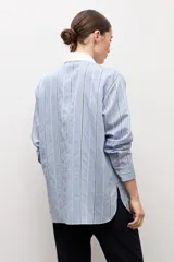 Camisa de manga larga celeste a rayas con pechera blanca lisa en el frente, cuello camisero y botones frontales.