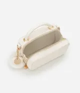 Bolso transversal tipo camera bag, color blanco con textura matelasse de rombos. Tiene correa fina ajustable y removible, cierre de cremallera y colgante de pompón.