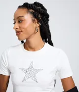 Remera de manga corta y cuello redondo, color blanco, confeccionada en algodón con elastano. Presenta una aplicación frontal de ojales metálicos formando una estrella.