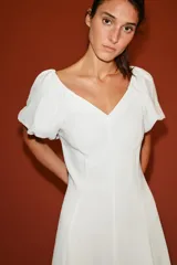Vestido midi de color blanco, con escote en V y mangas cortas abullonadas.