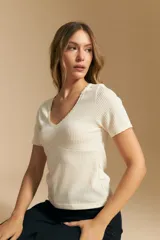 Remera de manga corta en tejido acanalado, con escote en V y detalles de puntilla en el borde del escote y en las mangas. Presenta un ajuste entallado al cuerpo.