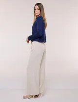 Cardigan corto azul marino de punto, con silueta entallada y largo a la cintura. Cuenta con un ribete decorativo que recorre el cuello redondo y la abertura frontal, integrando una cadena dorada en contraste. Posee bolsillos delanteros simulados y mangas largas.