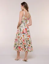 Vestido midi evasé de lino estampado con diseño floral multicolor sobre base beige. Cuenta con escote cuadrado, tirantes anchos y cierre invisible en la espalda.