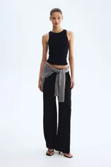Pantalón negro de tiro alto, confeccionado en tejido texturizado con corte holgado y piernas amplias. Cuenta con cintura elástica fruncida y cordón ajustable.
