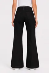 Pantalón de jean negro de tiro alto y corte flare, con bolsillos y aberturas con cierre en los botaguas delanteros.