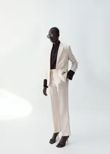 Pantalón de lino color beige, de diseño recto y tiro medio con trabillas. Cuenta con bolsillos laterales y cierre oculto.