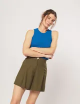 Short color beige de lino con tiro alto, elástico en la pretina trasera, cierre delantero con botón, tablas en el frente, bolsillos delanteros y dobladillo invisible.