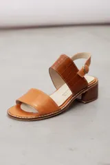 Sandalia de cuero vacuno color tostado con taco bajo y ancho, tira frontal lisa y tira ancha con textura de cocodrilo en el empeine, y tira ajustable al talón con hebilla metálica.