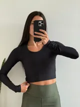 Top deportivo negro de manga larga, corte crop y tejido acanalado.