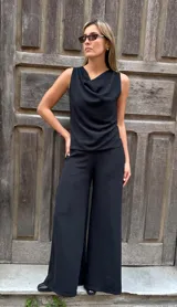 Blusa sin mangas de color negro, confeccionada en viscosa con lycra, con diseño fluido, cuello volcado y espalda descubierta con abertura vertical y lazo ajustable.