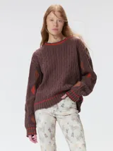 Sweater de punto con diseño de ochos en color verde, cuello redondo con detalle de franja en contraste, y apliques de rombos en las mangas. Presenta un bordado con la letra M en el pecho.