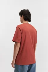 Remera blanca de manga corta con estampado frontal que incluye la palabra 'Savior' en letras cursivas negras y otros textos en tipografía sans-serif. Corte regular.