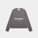 Sweater gris de punto con cuello redondo y mangas largas. Estampado frontal con el logo 'EME STUDIOS curated by ben ice' en color blanco.
