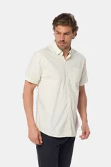 Camisa lisa de manga corta color crema, confeccionada en 100% algodón, con cuello abotonado y un bolsillo en el pecho.