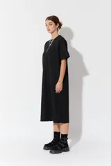 Vestido largo de manga corta y corte oversize, confeccionado en tejido con textura. Presenta cuello redondo y un parche decorativo en la parte posterior.