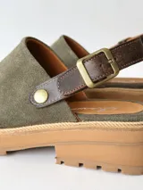 Zuecos de cuero color verde seco, con hebilla lateral y suela de goma.