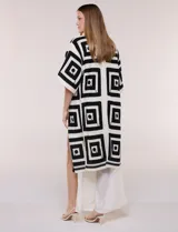 Cardigan largo confeccionado en tejido de punto calado estilo crochet, de color amarillo y blanco, con diseño geométrico de cuadrados, mangas amplias tipo kimono y corte abierto al frente.