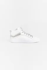 Zapatilla de caña media confeccionada en cuero vacuno blanco, con detalles de glitter plateado en los laterales y apliques de remaches metálicos. Cuenta con cierre lateral para facilitar el acceso y suela de caucho.