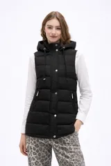 Chaleco acolchado negro con capucha ajustable mediante cordones, cierre frontal con botones a presión y bolsillos laterales con cierre.