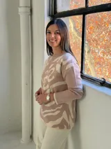 Sweater de tejido de punto con diseño abstracto en tonos beige y crema, de corte holgado, cuello redondo y manga larga.