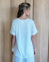 Remera blanca de algodón tramado, con escote en V y mangas cortas holgadas con dobladillo.