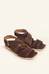 Sandalias bajas de cuero negro con tachas plateadas, tiras cruzadas y hebilla al tobillo.