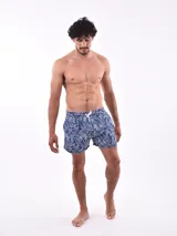 Short de baño blanco con estampado de hojas en tonos azules y rosados, cintura elástica con cordón ajustable.