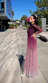 Vestido largo de manga larga con efecto degradado que va desde un tono fucsia oscuro en la parte superior hasta un rosa claro en el ruedo. Presenta un corte ajustado y cuello redondo.