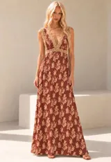 Vestido largo marrón con estampa floral en tonos tostados, escote en V profundo con terminaciones de encaje en el busto y los tirantes, y espalda escotada con lazo fino.