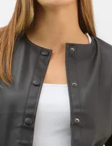 Chaqueta Sioni con frente de cuero sintético y mangas y espalda de tejido de punto. Presenta cuello a la base, cierre frontal con botones a presión y bolsillos delanteros.